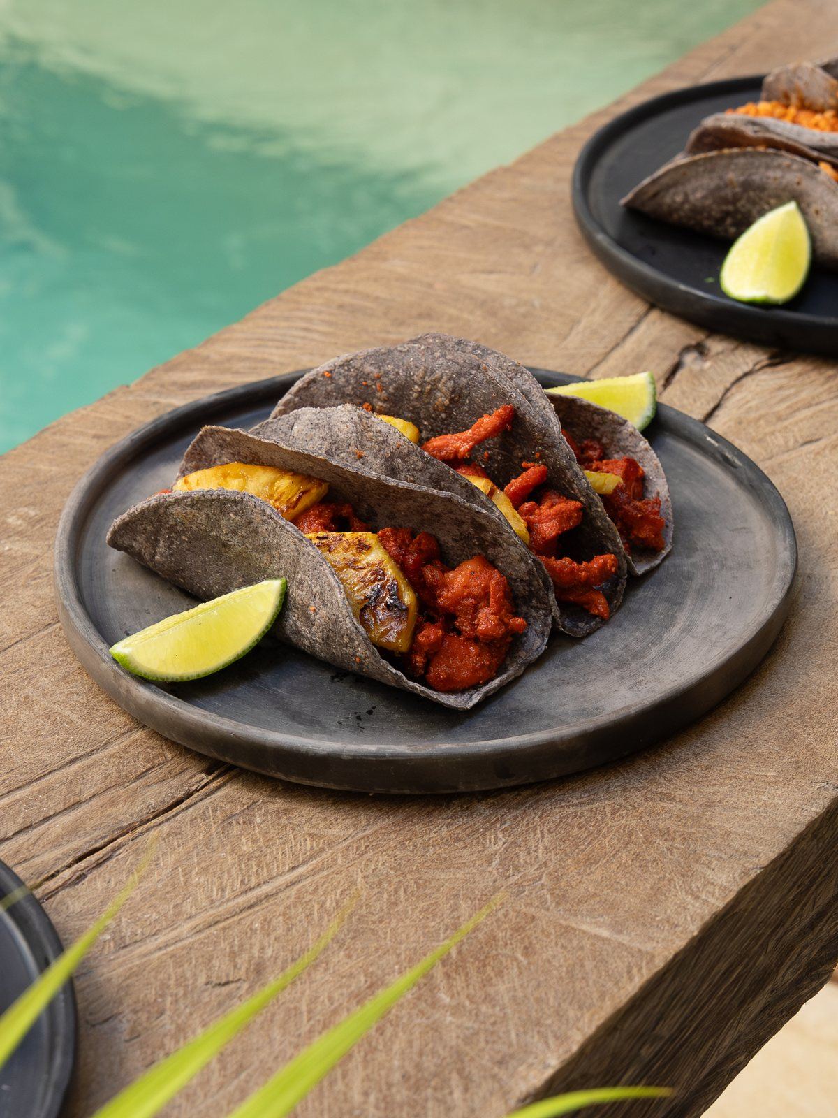Tacos al pastor on blue tortillas beside the pool