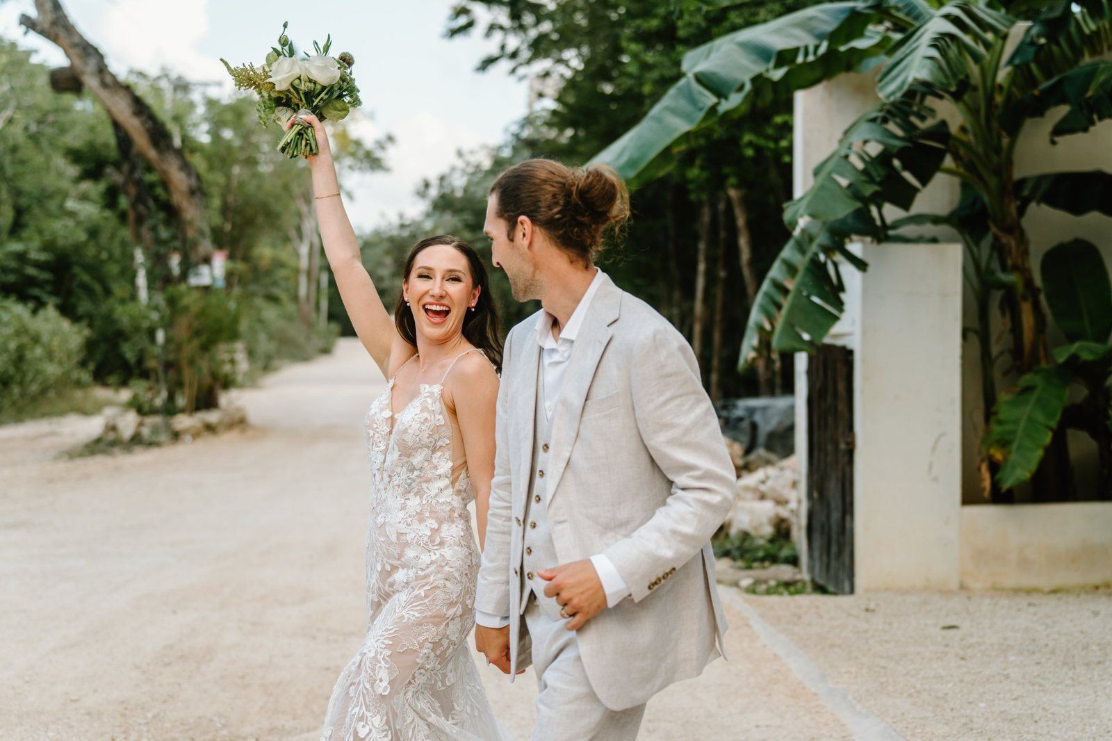 The couple leaving the villa, the bride raising her bouquet